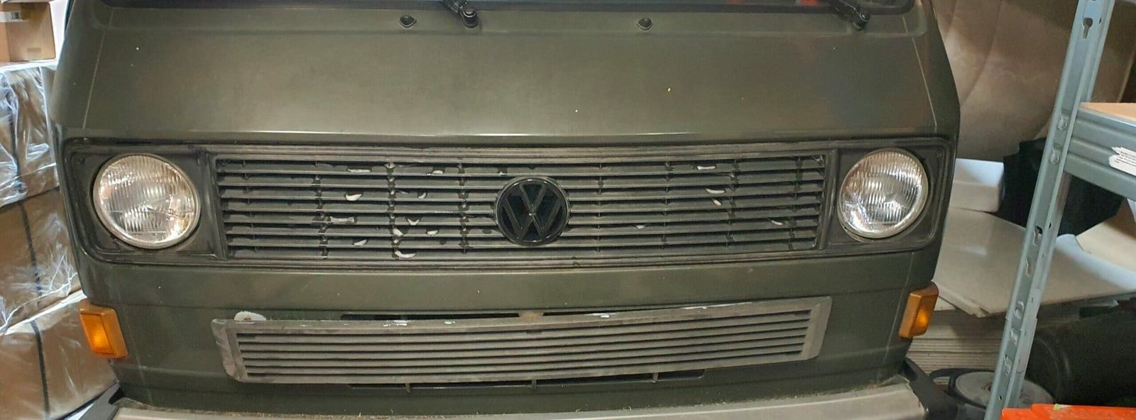 Front des VW T3 mit Kühlergrill, VW-Zeichen und runden Scheinwerfern in der Werkstatt